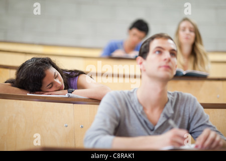 Schüler hören Dozent, während ihre Klassenkameraden schläft Stockfoto