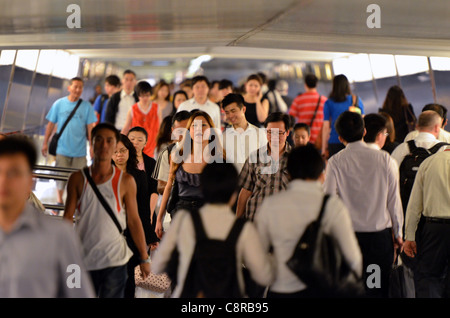 Massen von chinesischen Büroangestellten fließt entlang einen erhöhten Laufsteg im central Business District. Stockfoto