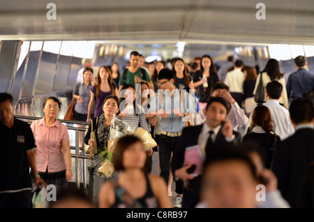 Massen von chinesischen Büroangestellten fließt entlang einen erhöhten Laufsteg im central Business District. Stockfoto