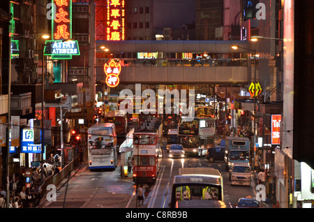 Eine typische Hongkong Straßenszene Neonlichter und Staus mit Straßenbahnen, Bussen, Autos und Menschen. Stockfoto