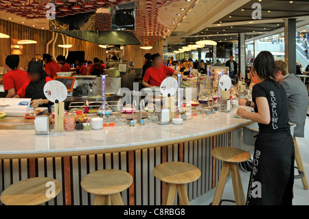 People & YO Sushi Restaurant Geschäftsessen in Schüsseln auf einem rotierenden Förderband zeigen Westfield Shopping Centre im Stratford City London England UK Stockfoto