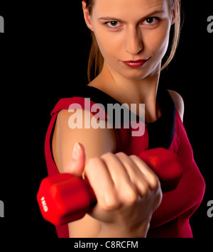 Schwere Sportlerin zeigt rote Hantel auf schwarzem Hintergrund Stockfoto