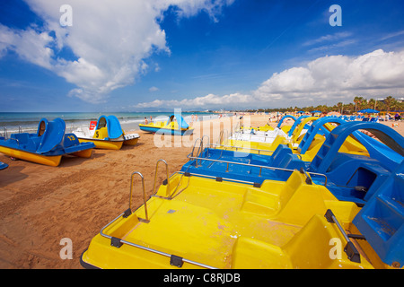 Lebhafte gelbe und blaue Tretboote zum Mieten am Sandstrand Llevant in Salou, Katalonien, Spanien. Stockfoto