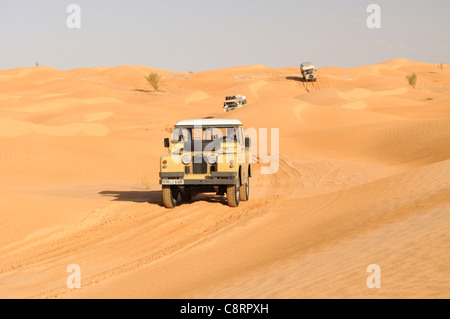 Afrika, Tunesien, nr. Tembaine. Wüste Reisende mit ihren historischen Serie Landrover quer durch eine Sandfield in der Nähe... Stockfoto