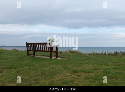 Denkmal-Bank mit Blumen mit Blick auf South Bay Strand in Bridlington, Yorkshire, Großbritannien Stockfoto