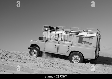 Afrika, Tunesien, nr. Tembaine. Wüste Reisende fahren ihre 1975 Land Rover Serie 3 Kombi durch eine Sandfield... Stockfoto