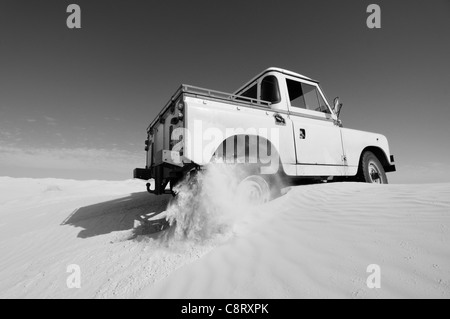 Afrika, Tunesien, nr. Tembaine. Wüste Reisende fahren seine 1964 Land Rover Serie 2a LKW-Kabine durch eine Sandfield nah an... Stockfoto