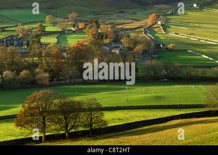 Die ersten Sonnenstrahlen treffen das bunte Herbstlaub Arncliffe in Littondale, Yorkshire Stockfoto