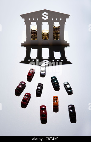 Erhöhte Ansicht von Spielzeugautos vor Modell der Bank mit Dollarzeichen Stockfoto