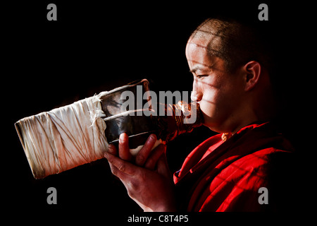 Ein junger Mönch mit Blick auf die aufgehende Sonne weht eine Conch Shell Trompete, Galden Namgey Lhatse Kloster, Indien Stockfoto