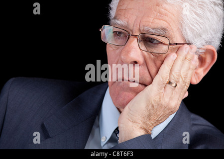 Senior-Unternehmer denken mit seiner Hand am Kinn (isoliert auf schwarz) Stockfoto