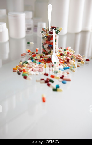 Becher gefüllt mit Kapseln und Tablettenfläschchen im Hintergrund Stockfoto