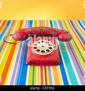 Studioaufnahme von Telefon mit Wählscheibe auf gestreiften Hintergrund Stockfoto