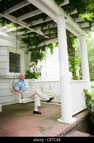 USA, New York State, Old Westbury, Senior Mann sitzt auf der Veranda-Schaukel Stockfoto