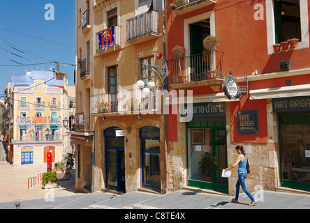 Eine Frau spaziert an alten Gebäuden mit bunten Fassaden in der Altstadt von Tarragona, Katalonien, Spanien. Stockfoto