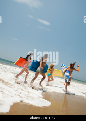 USA, California, Malibu, Gruppe von jungen attraktiven Frauen laufen ins Wasser mit Surfbrettern Stockfoto