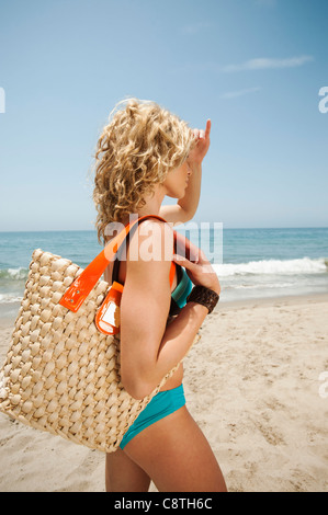 USA, California, Malibu, junge attraktive Frau mit Stroh Tasche am Sandstrand Stockfoto