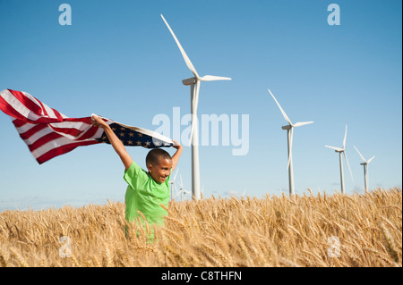 USA, Oregon, Wasco, junge amerikanische Flagge im Weizenfeld mit Windkraftanlagen im Hintergrund Stockfoto