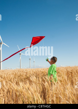 USA, Oregon, Wasco, junge spielt mit Drachen im Weizenfeld, Windkraftanlagen im Hintergrund Stockfoto