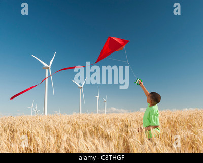 USA, Oregon, Wasco, junge spielt mit Drachen im Weizenfeld, Windkraftanlagen im Hintergrund Stockfoto