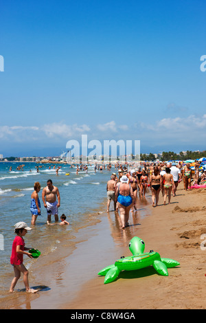 Die Leute laufen am überfüllten Els Pilons Beach in Salou, Katalonien, Spanien. Stockfoto