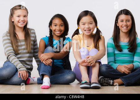 Studio-Porträt von vier Mädchen sitzen nebeneinander Stockfoto