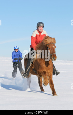 Zwei Mädchen, die Spaß beim Skijöring mit einem Islandpferd Stockfoto