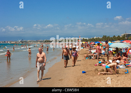 Die Leute laufen am überfüllten Els Pilons Beach in Salou, Katalonien, Spanien. Stockfoto