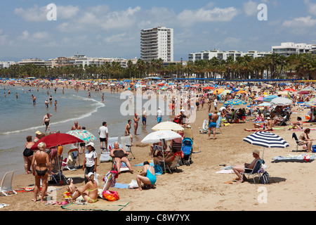 Touristen sonnen sich am überfüllten Els Pilons Strand in Salou, Katalonien, Spanien. Stockfoto