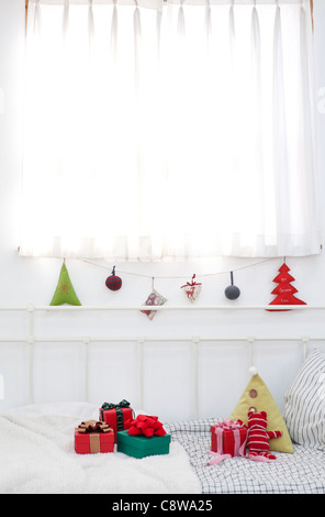 Weihnachtsschmuck hängen, String und Weihnachts-Geschenk-Boxen auf Couch Stockfoto