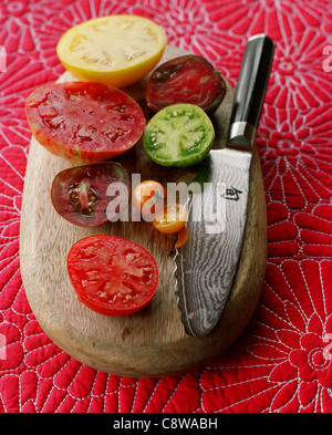 Verschiedene saftige Tomatenscheiben auf Schneidebrett mit Messer Stockfoto