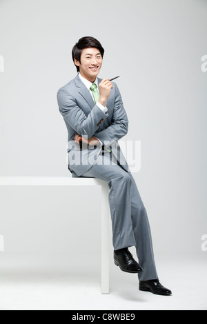 Portrait Of Smiling asiatischen Geschäftsmann auf Schreibtisch mit Stift Stockfoto