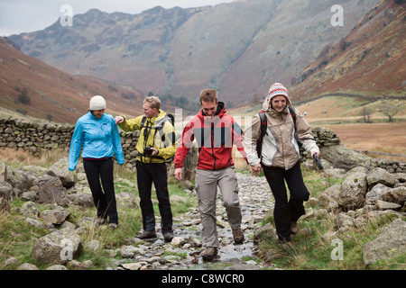 Vier junge tausendjährigen Menschen zu Fuß beim Spaziergang in Langstrath Tal in den Bergen des Lake District National Park Cumbria England Großbritannien Stockfoto