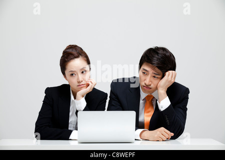 Langeweile asiatische Geschäftsfrau Geschäftsmann sitzen am Schreibtisch mit Laptop Stockfoto