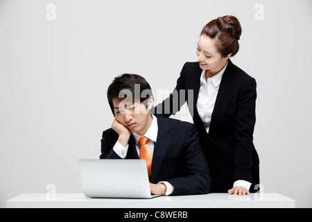 Asiatische Geschäftsfrau tröstet den Geschäftsmann am Schreibtisch arbeiten Stockfoto