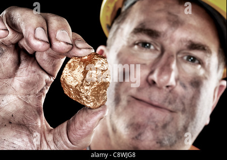 Ein Goldgräber zeigt einen golden Nugget frisch ausgegraben aus einer Mine. Stockfoto