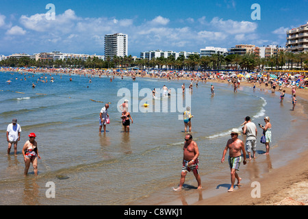 Die Leute laufen am überfüllten Els Pilons Beach in Salou, Katalonien, Spanien. Stockfoto