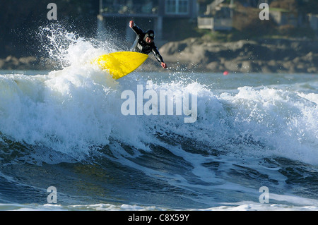 Eine Surfer reitet eine Welle Größe Strand in Devon im November. Stockfoto