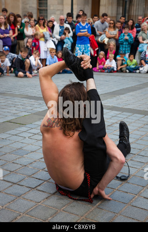 Männlicher Entertainer durchführen zur Audienz im Freien durch Verdrehen zu unnatürlichen Positionen während des Edinburgh Fringe Stockfoto