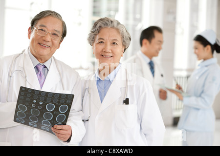 Zwei Ärzte untersuchen ein CAT-Scan mit einem Arzt und Krankenschwester im Hintergrund Stockfoto