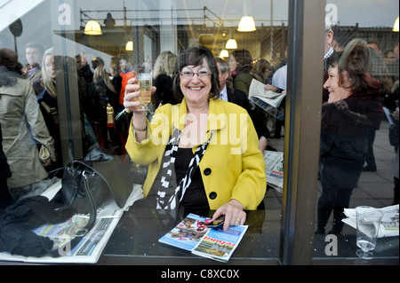Ein Frau Punter feiert hält ein Glas Champagner nach eine gewonnene Wette bei Pferderennen in Cheltenham am Ladies Day. Stockfoto