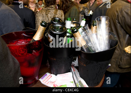 Leere Flaschen Champagner umgedrehten in Eiswürfelbehälter mit Wettscheine links auf dem Tisch Stockfoto