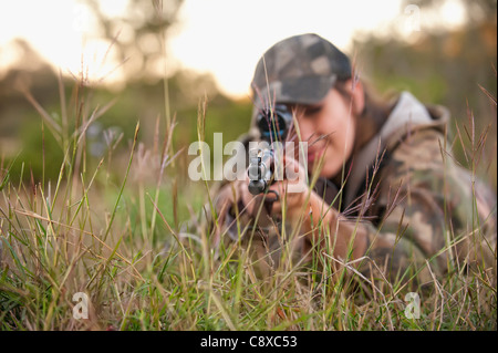 Jagd-Frau liegt auf dem Rasen soll eine Gewehr Waffe schießen Stockfoto