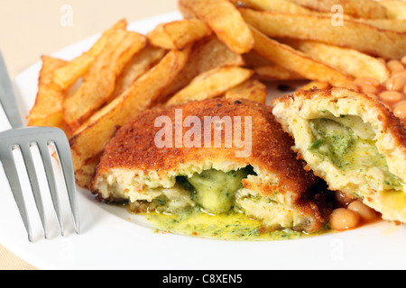 Ein Huhn Kiew zeigen die Knoblauchbutter und Petersilie füllen, close-up mit gebackenen Bohnen und einer Gabel. Stockfoto