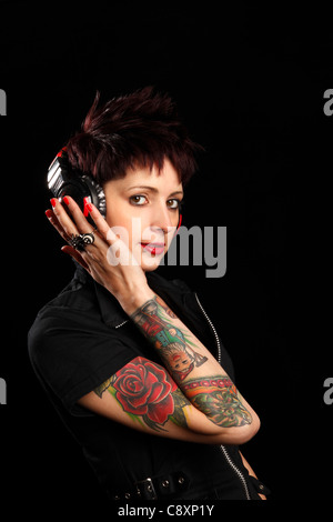 junge Frau mit Tattoos auf dem Arm, das Anhören von Musik über Kopfhörer Stockfoto