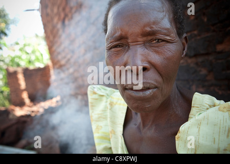 Frau Nasabu Kadama (50) sitzt vor ihrem beschädigten Haus in Nsinze Dorf, Namutumba Bezirk, Osten von Uganda. Stockfoto