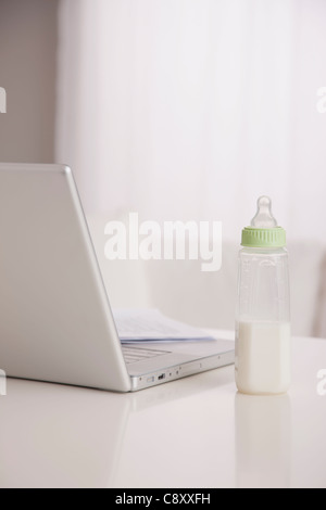 USA, Illinois, Metamora, Baby-Flasche mit Milch und Laptop auf Tisch Stockfoto