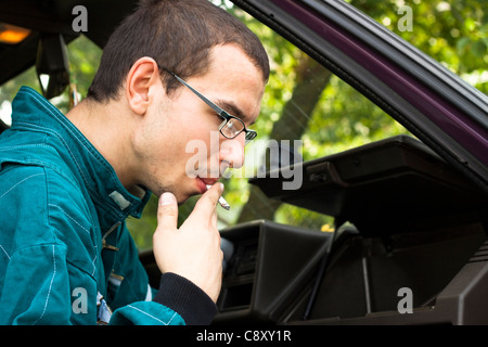 Junge Arbeiter Rauchen im Auto. Stockfoto