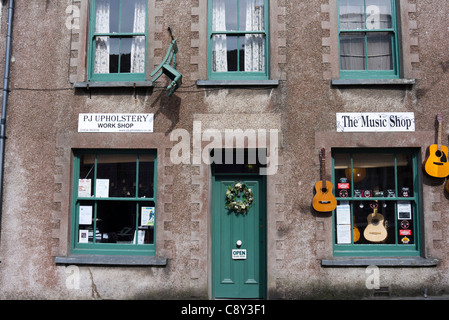 Gitarren und Stühle hängt an der Wand außerhalb der Musik und der Polsterung Geschäfte in Narberth, Pembrokeshire, Wales Stockfoto