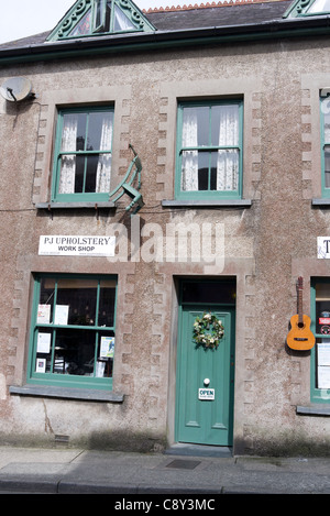 Gitarren und Stühle hängt an der Wand außerhalb der Musik und der Polsterung Geschäfte in Narberth, Pembrokeshire, Wales Stockfoto